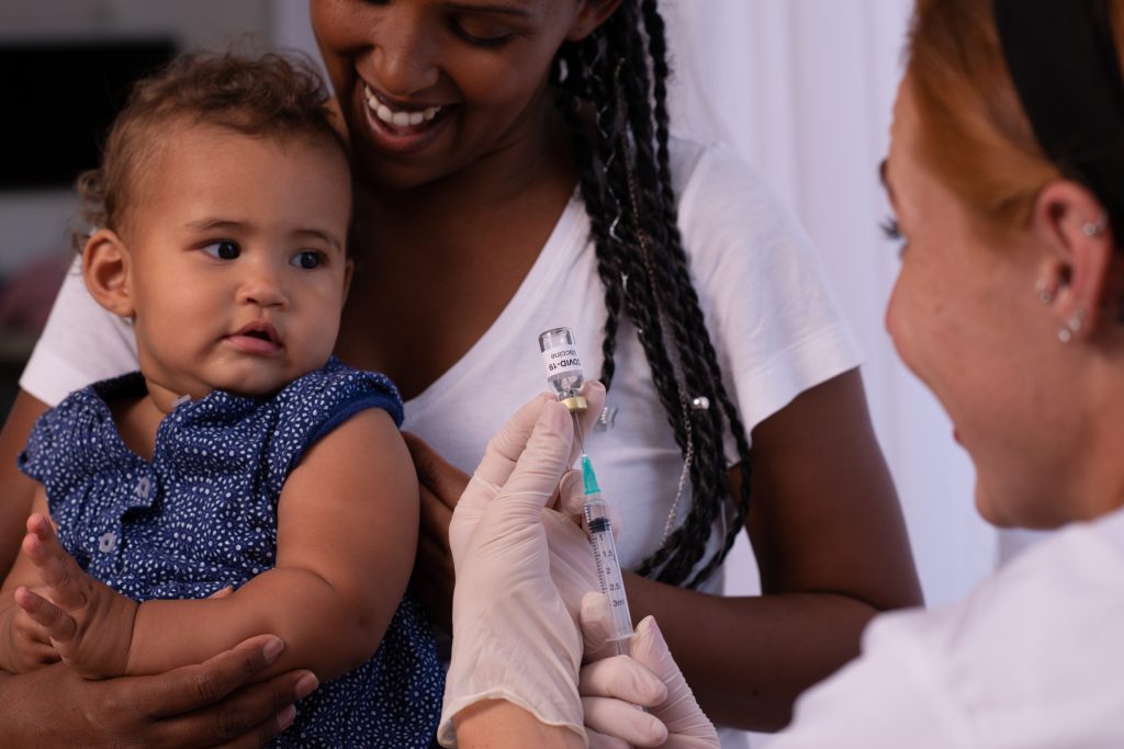 The pediatrician or nurse vaccinating baby child patient with a Covid-19 vaccine.