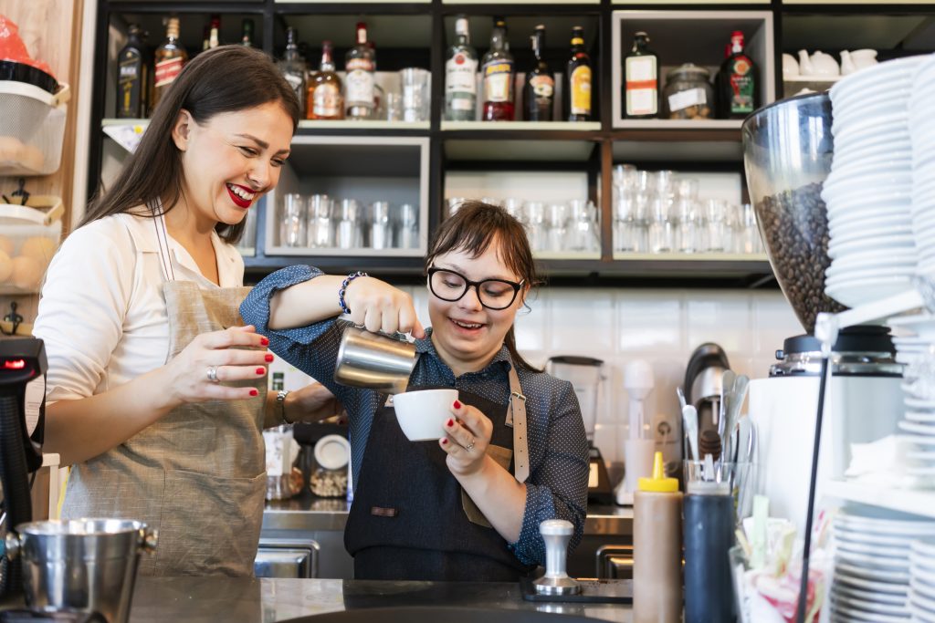 Young woman with Down Syndrome working at cafe preparing coffee