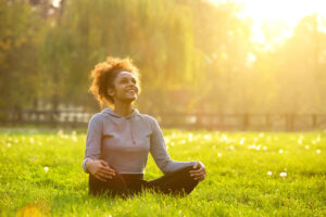 woman meditating in a feild about emotional wellness