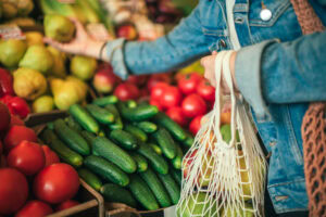 a womans hand selecting a pear from a fruit stand